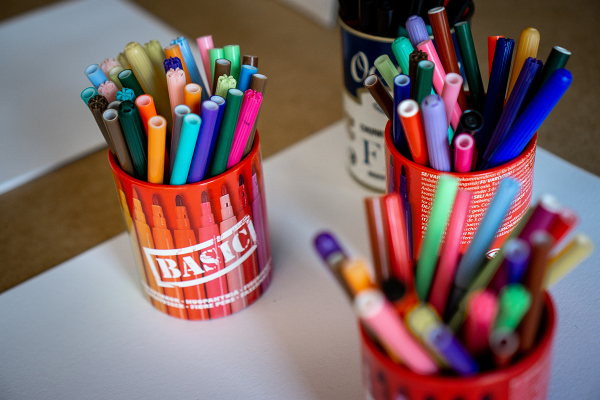 Färgglada pennor nerstuckna i en burk ståendes på ett bord