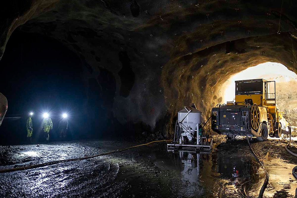 Foto inifrån tunneln med maskin och tre arbetare